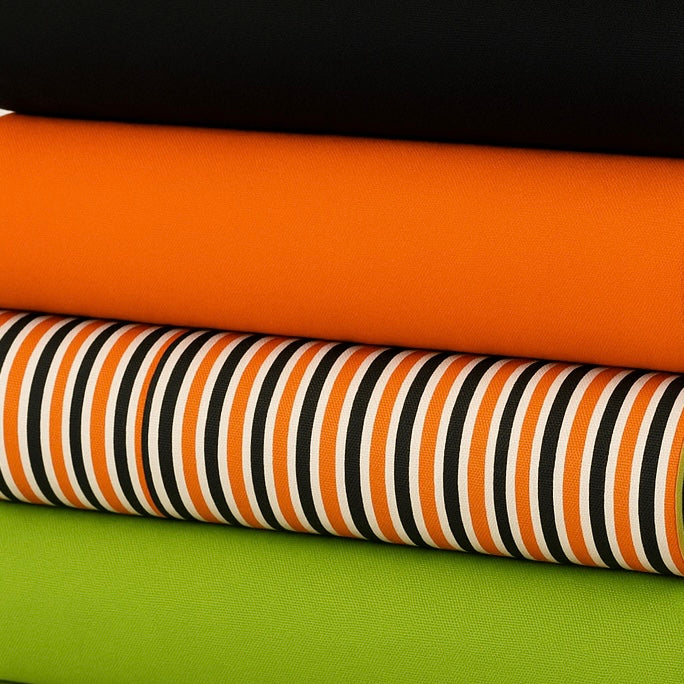 Close-up of striped Halloween fabric โ vertical orange, black, and white stripes with bold contrast details.