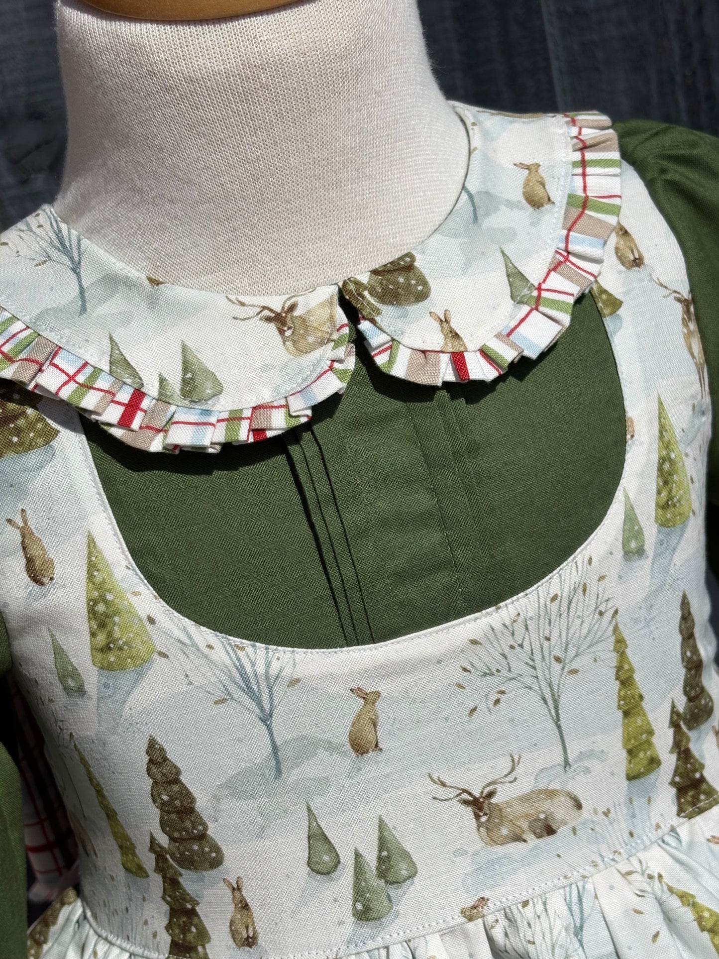 Close up of Peter Pan collar with plaid trim and pin tucks in hunter green solid fabric