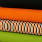 Close-up of striped Halloween fabric – vertical orange, black, and white stripes with bold contrast details.