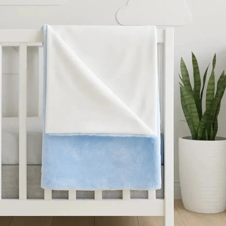 White crib with a blue double sided fleece blanket draped over it, embroidered with custom name.