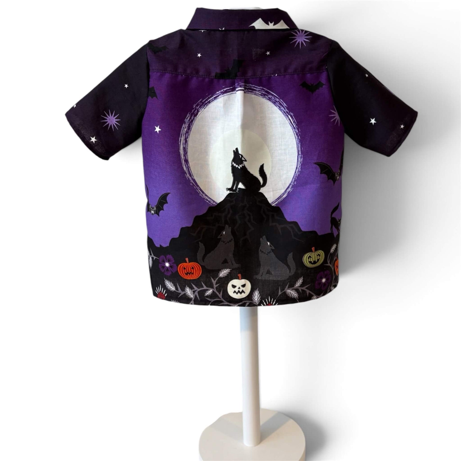 A short-sleeve button-up shirt featuring a Halloween-themed graphic print with a howling wolf, full moon, bats, jack-o'-lanterns, and cats on a purple and black background.