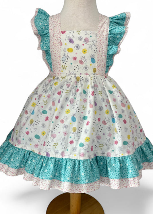 Children's dress with floral pattern and turquoise trim on a mannequin against a white background