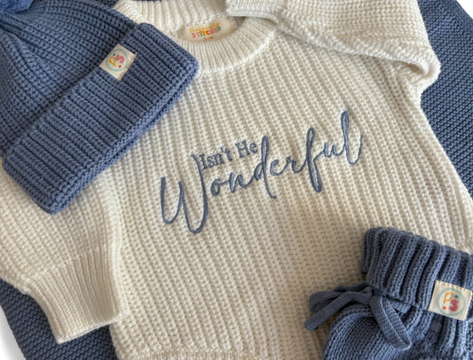 Baby sweater with 'Isn't He Wonderful' text, blue hat, and pants on a white background