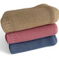 Three stacked knit blankets in beige, pink, and blue on a white background