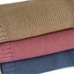 Three stacked knit blankets in beige, pink, and blue on a white background