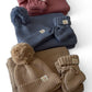 Stack of winter accessories including hats and mittens on a white background