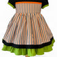 Handmade toddler Halloween dress – black bodice with orange accent, puff sleeves with green trim, and striped orange, black, and white twirl skirt.
