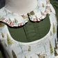 Close up of Peter Pan collar with plaid trim and pin tucks in hunter green solid fabric