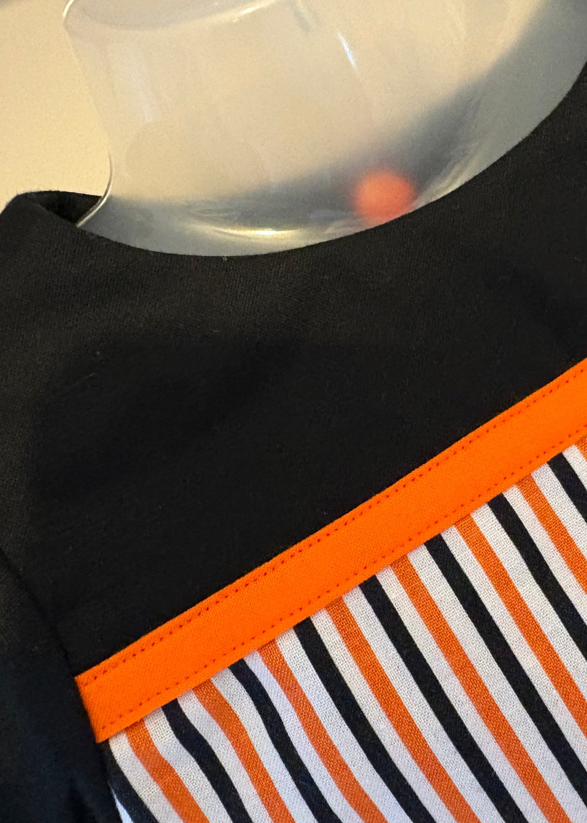 Handmade Halloween baby romper – striped orange, black, and white fabric with green trim and puff sleeves, perfect for spooky season.