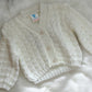 White baby cardigan on a fluffy white surface