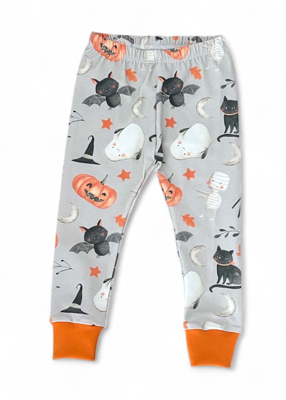 Halloween-themed children's pants with pumpkins, cats, and bats on a gray background.
