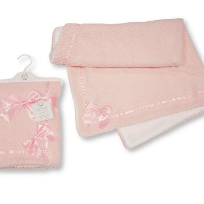 A light pink baby blanket with a textured waffle pattern, delicate pink trim, and a matching satin bow, shown both folded on a hanger and unfolded on a white background.