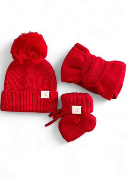 Red knit baby hat with pom-pom, matching headband, and booties