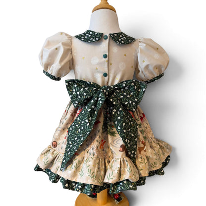 Back of the Snowdrop Christmas dress on a dress form, showing green popper fastenings, a large floral sash bow and a double-ruffle hem.