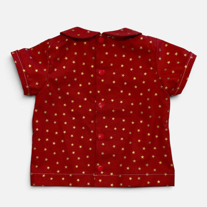 A red short-sleeve button-up shirt with a repeating pattern of small gold stars, laid flat against a light gray background.