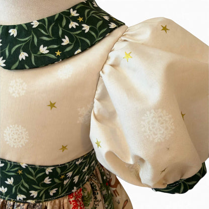 Close-up of the Snowdrop dress’s deep-green Peter Pan collar with white snowdrops and gold stars above a cream snowflake-and-star bodice.
