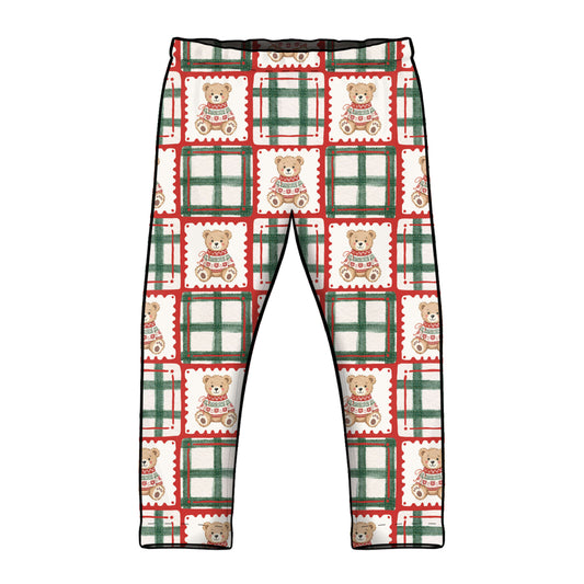 A pair of children's leggings with an all-over Christmas-themed pattern featuring teddy bears in sweaters inside postage stamp designs and green plaid borders, shown against a plain white background.