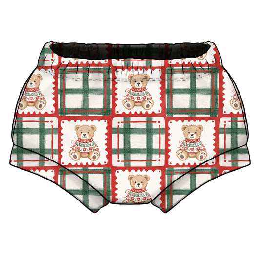 A pair of toddler shorties/bummies featuring a festive holiday print with teddy bears in Christmas sweaters, red and green plaid patterns, and elasticated waist