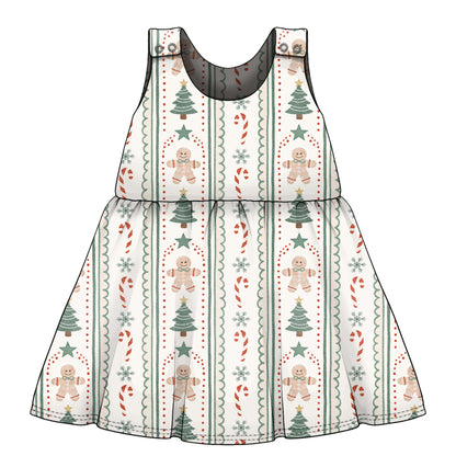 A sleeveless baby dress with a festive Christmas print featuring gingerbread men, Christmas trees, candy canes, and snowflakes on a white background.