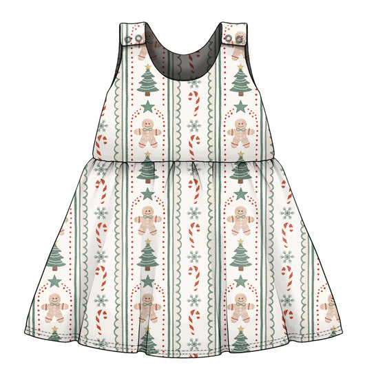 A sleeveless baby dress with a festive Christmas print featuring gingerbread men, Christmas trees, candy canes, and snowflakes on a white background.