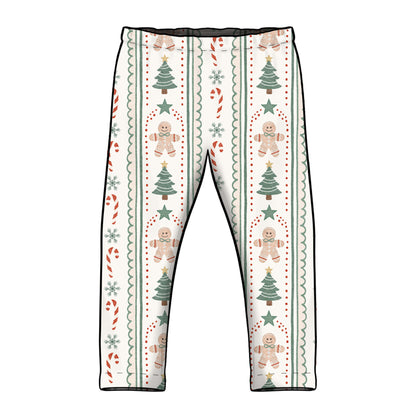 A pair of children's leggings with a festive Christmas pattern featuring gingerbread men, Christmas trees, candy canes, and snowflakes on a cream background. Leggings have elasticated waist and straight classic hemmed cuffs. 