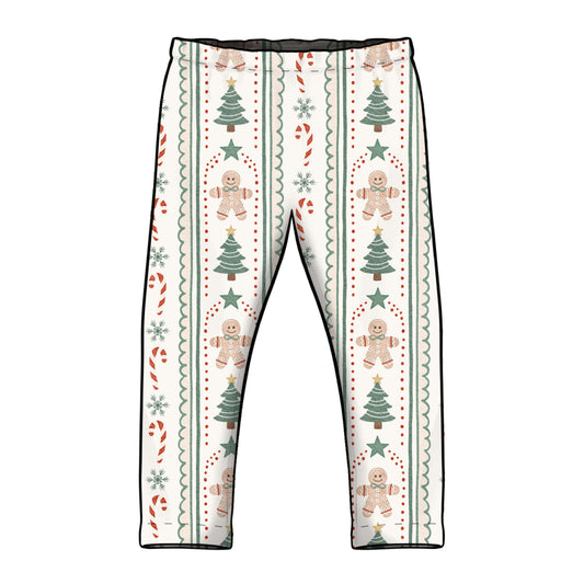 A pair of children's leggings with a festive Christmas pattern featuring gingerbread men, Christmas trees, candy canes, and snowflakes on a cream background. Leggings have elasticated waist and straight classic hemmed cuffs. 
