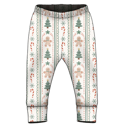 A pair of baby pants with an all-over Christmas pattern featuring gingerbread men, Christmas trees, candy canes, and snowflakes on an off-white background.