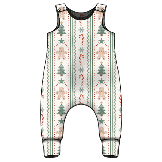 A sleeveless baby romper with an all-over Christmas holiday print featuring gingerbread men, Christmas trees, candy canes, and snowflakes on a cream background with black trim.