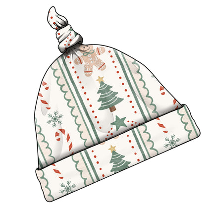 A knotted baby hat with a festive Christmas pattern featuring green trees, red candy canes, snowflakes, and stars on an off-white background.