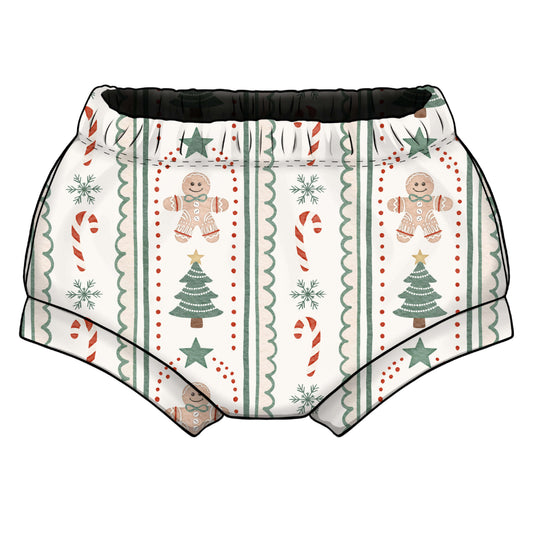 A pair of shorties/bummies with a festive Christmas print, featuring gingerbread men, candy canes, snowflakes, and Christmas trees on a cream background with an elastic waistband.