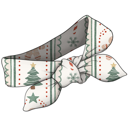 A fabric headband with a festive Christmas pattern, featuring green trees, snowflakes, stars, and red dots on a cream background.