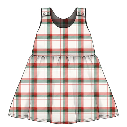 A sleeveless plaid children's dress. The dress has a white base with red and green tartan lines, a gathered waist seam, and small decorative poppers at the shoulder straps.