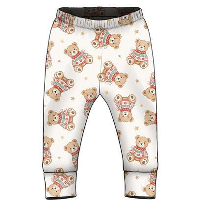 A pair of children's pants with an all-over print of teddy bears wearing red and green sweaters, set against a plain white background.