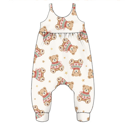 A baby romper or jumpsuit with an all-over print of teddy bears wearing red and green knit sweaters and small gold stars on a cream background.