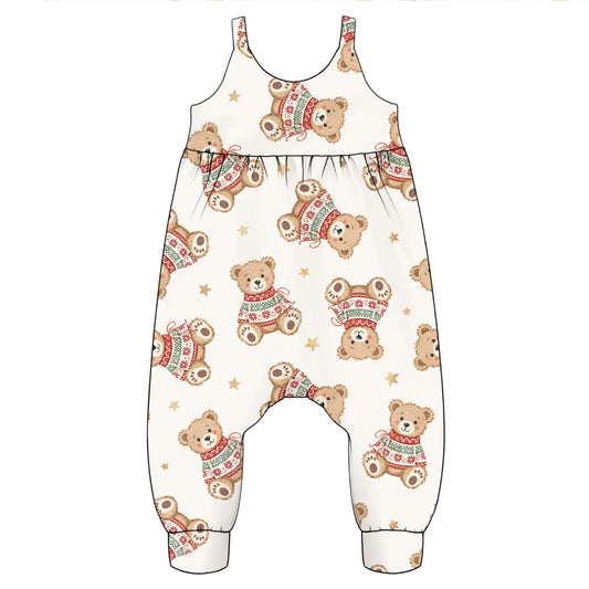 A baby romper or jumpsuit with an all-over print of teddy bears wearing red and green knit sweaters and small gold stars on a cream background.