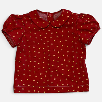 A red short-sleeve baby top with a Peter Pan collar and an all-over gold star pattern, laid flat against a light gray background.