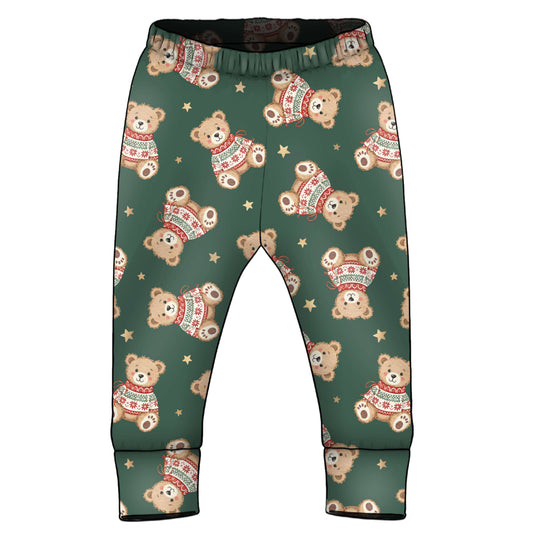 A pair of toddler pants with an all-over print of teddy bears wearing Christmas sweaters and small gold stars on a dark green background.