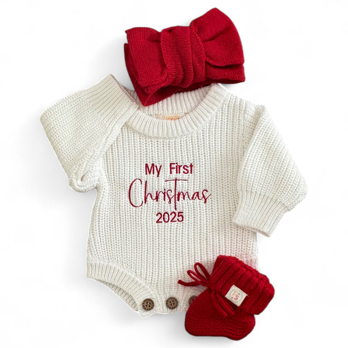 Baby onesie with 'My First Christmas 2025' text, red bow, and booties on a white background