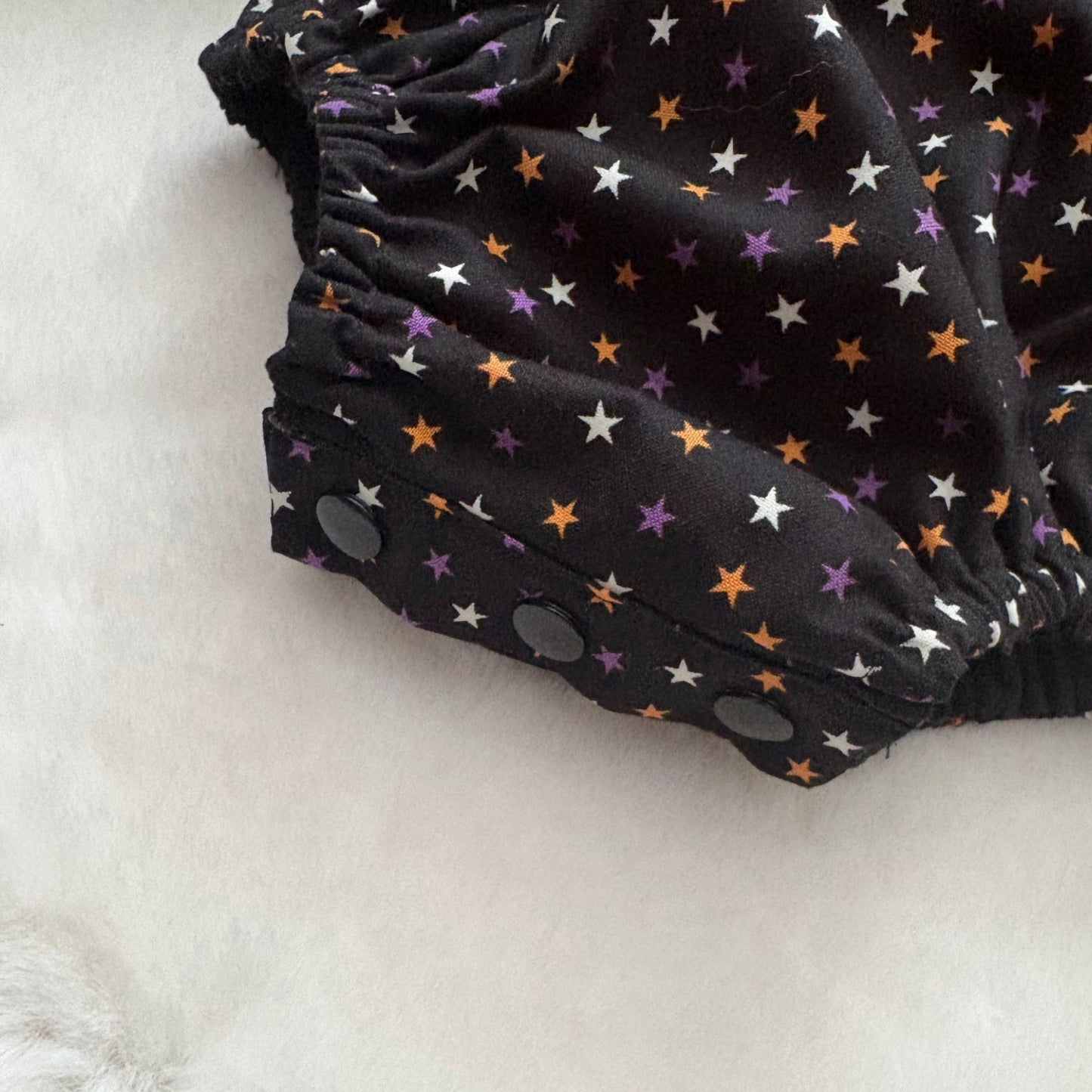 popper closure on a baby cotton woven romper for ease of nappy changing 