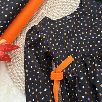 A close-up of a black romper showing the side tie straps and neckline